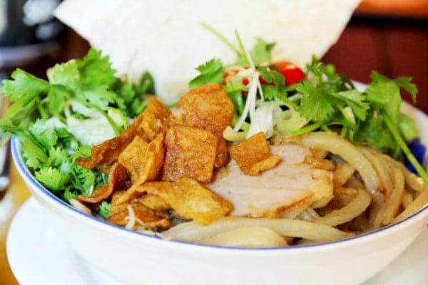 7. Cao lầu: Vẻ đẹp yên bình là một trong những điều giúp Hội An trở thành điểm đến yêu thích của nhiều du khácch. Thế nhưng, không chỉ để tìm kiếm những phong cảnh đẹp cùng kinh nghiệm văn hóa phong phú, du khácch đến Hội An còn bị quyến rũ bởi hương vị ẩm thực đặc sắc, trong đó có cao lầu. Cao lầu là món ăn gắn liền với hình ảnh phố cổ. Món ăn là sự kết hợp của sợi mì vàng, tôm, thịt heo, các loại rau sống địa phương nổi tiếng, giá trụng, da heo, tóp mỡ chiên giòn và rất ít nước dùng. Khi ăn cao lầu bạn sẽ thích thú khi được trải nghiệm cảm giác sựt sựt của sợi mì, đủ hương vị chua, cay, mặn, ngọt của nước mắm, rau sống, rau thơm, nước tương và tép mỡ tan trong miệng.